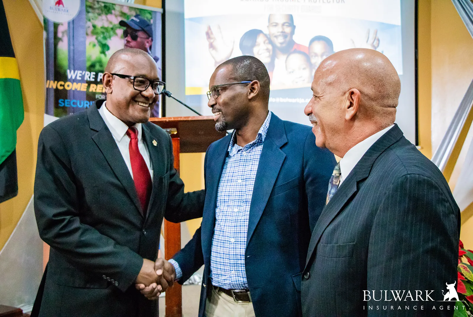 Three men in suits greeting each other at a Guards Income Protector event